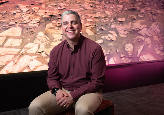 A man sits in front of an image of mars