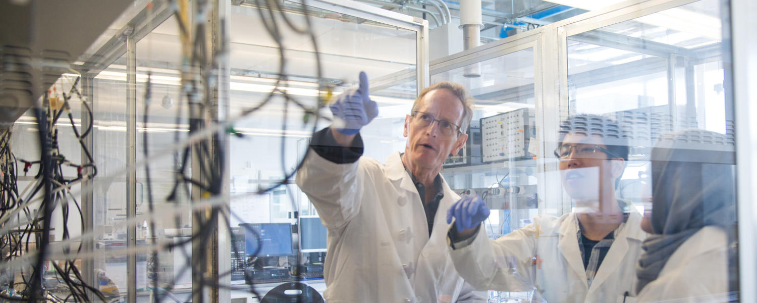 three people wearing lab coats in a lab.