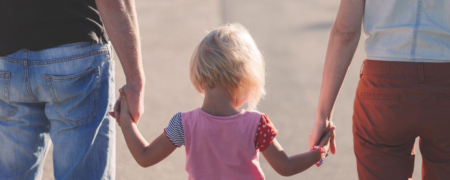 Mom and dad holding the daughters hands walking away.