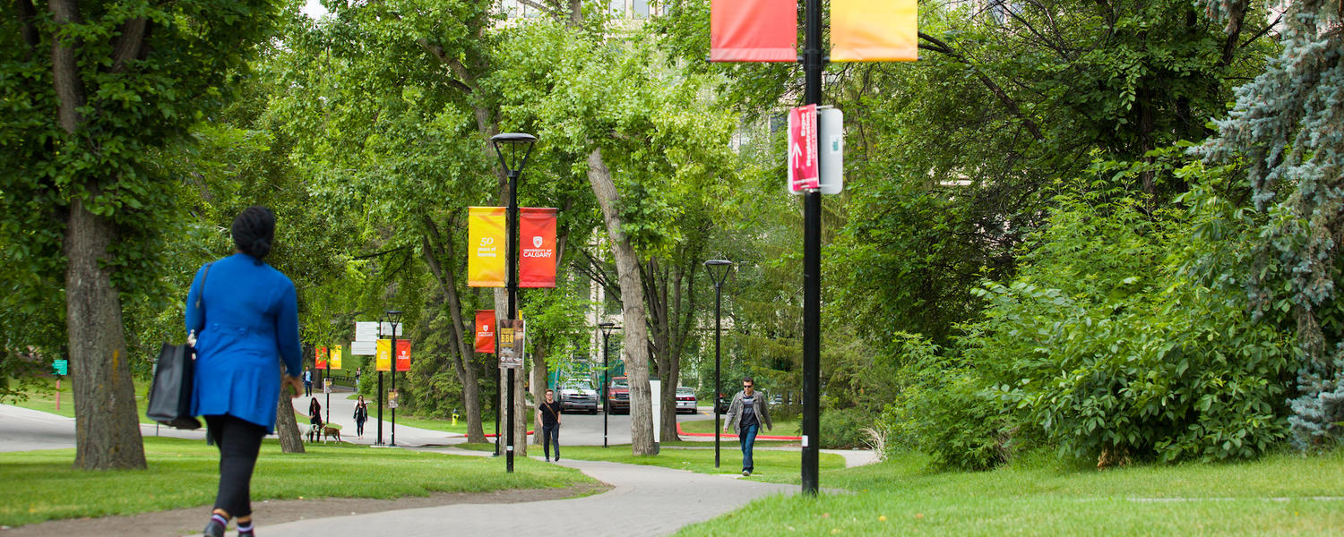 woman in blue coat walks across campus in summer