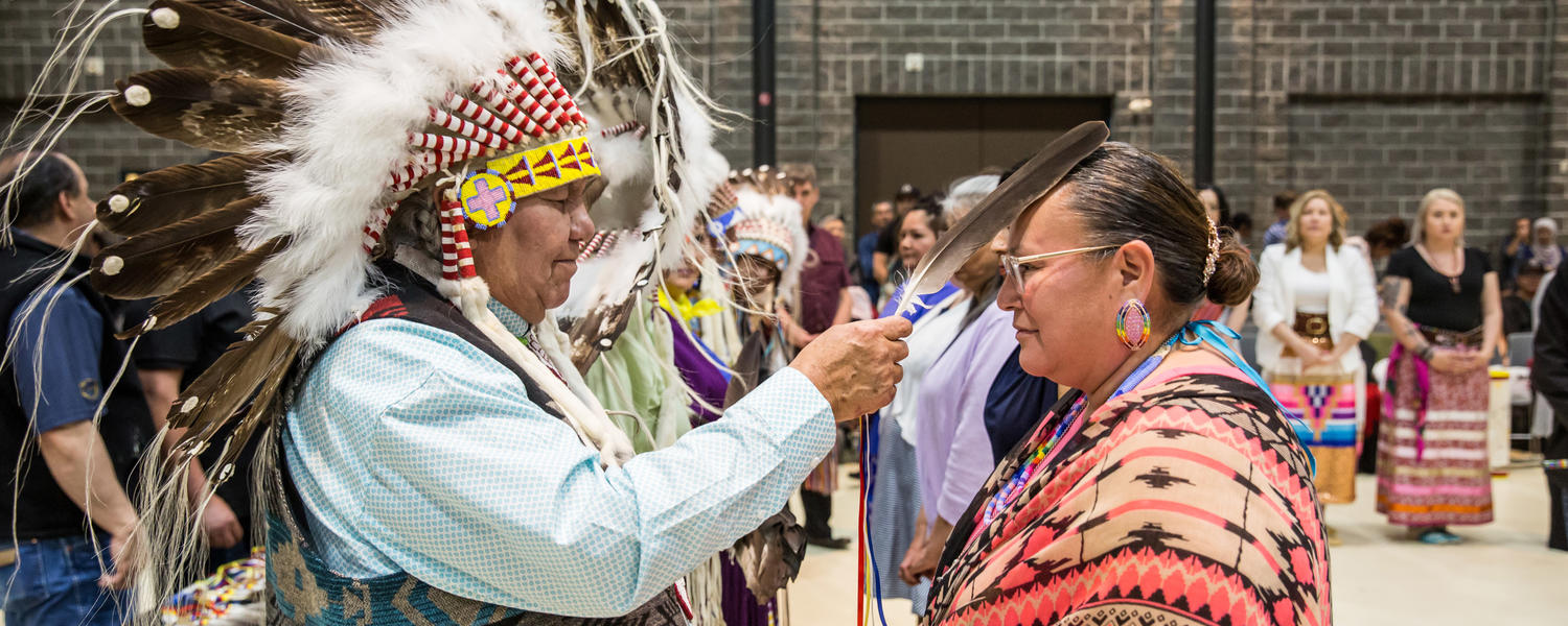 Dr. Reg Crowshoe honours an Indigenous graduate with an eagle feather