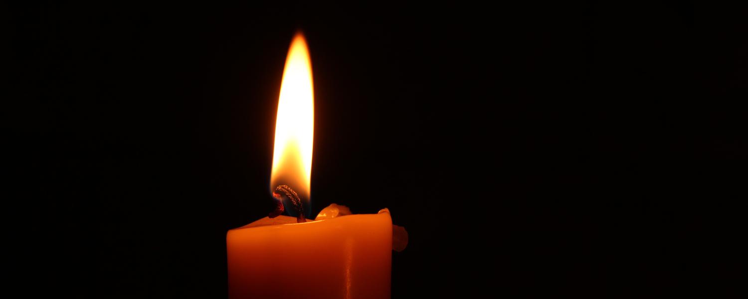 single candle burning on a black background