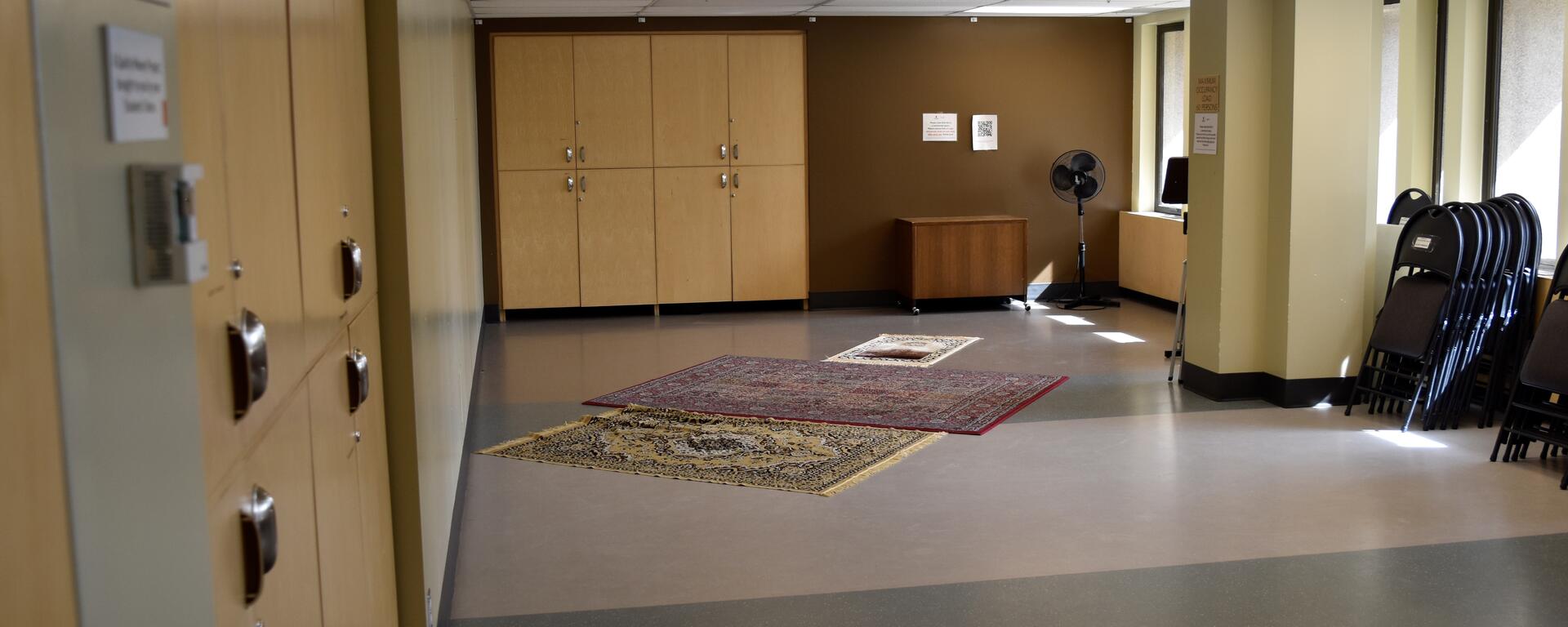 a room with windows, cabinets, and prayer mats on the floor