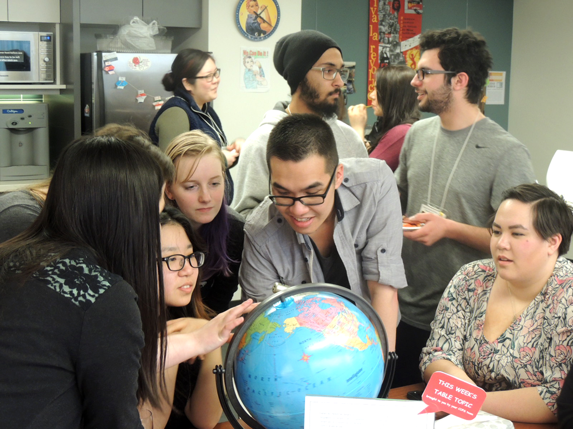 student volunteers gather around a globe