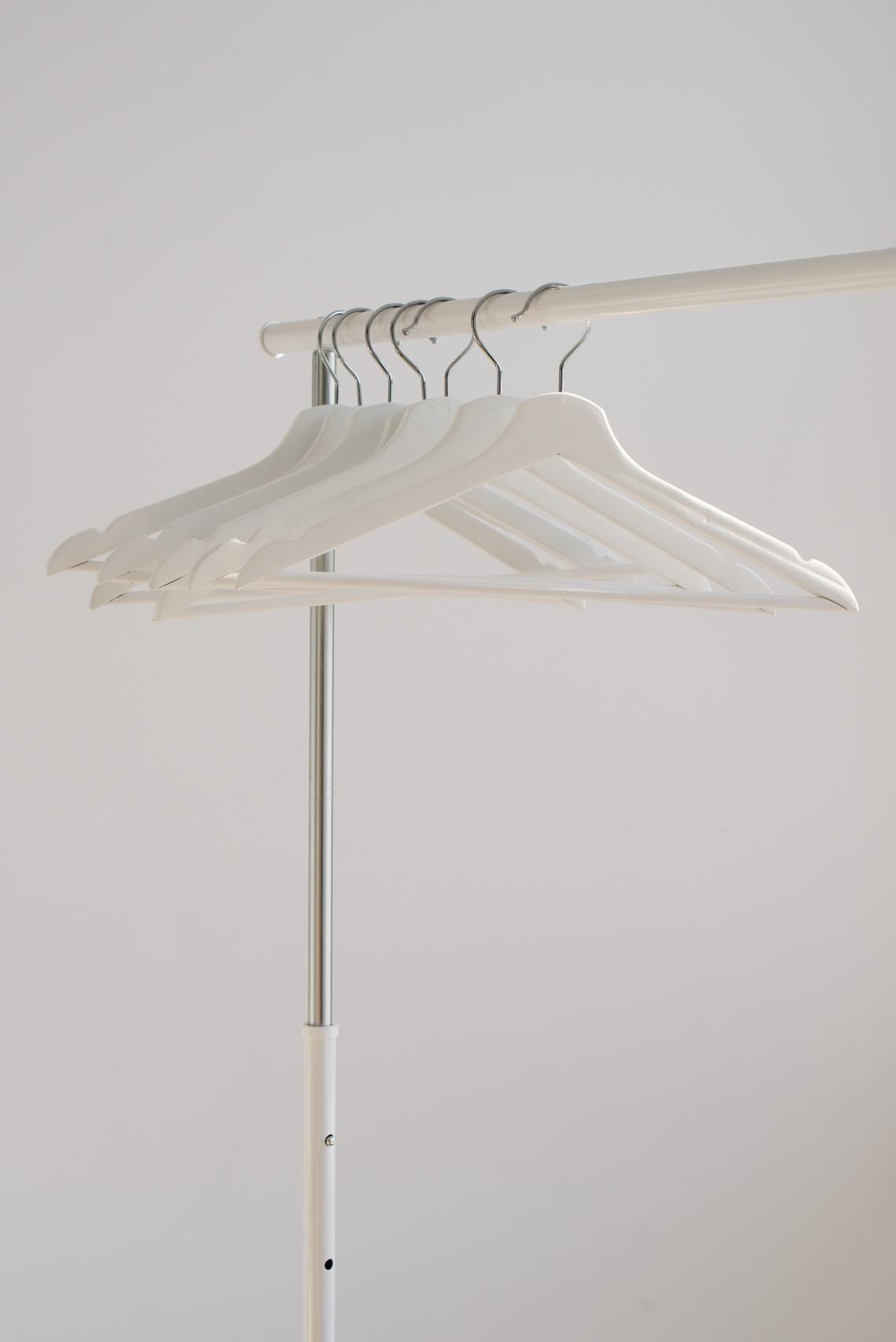 White hangers hanging on a metal clothing rack