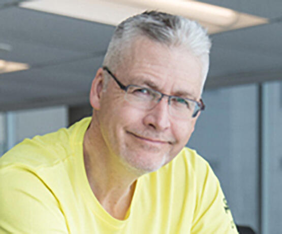 A man with gray hair and glasses wearing a neon yellow workout top