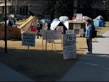 A student stops to read signs at a tent city set up outside MacEwan Hall by students protesting tuition hikes, 1999.