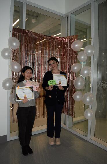 Two mentors pose with certificates and thank you cards.