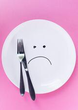 an empty plate that has a sad face drawn on it with black marker