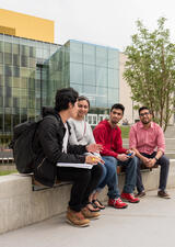 four students sitting outside on main campus 