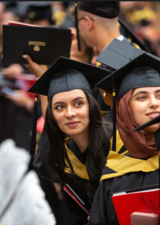 Photo of a group of people in graduation gowns and caps