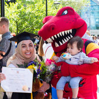 Woman holding her degree with Rex and her baby 