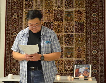 a man wearing a plaid shirt reads from a book