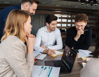 Group of people working together on a new project while sitting at the table in the office by Dean Drobot