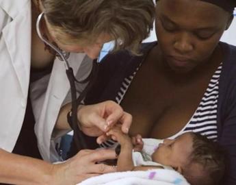 A doctor and a female tending to a baby 