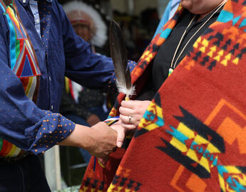 A person shaking hand with an indigenous person.