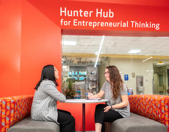 Two students seated in front of the Hunter Hub