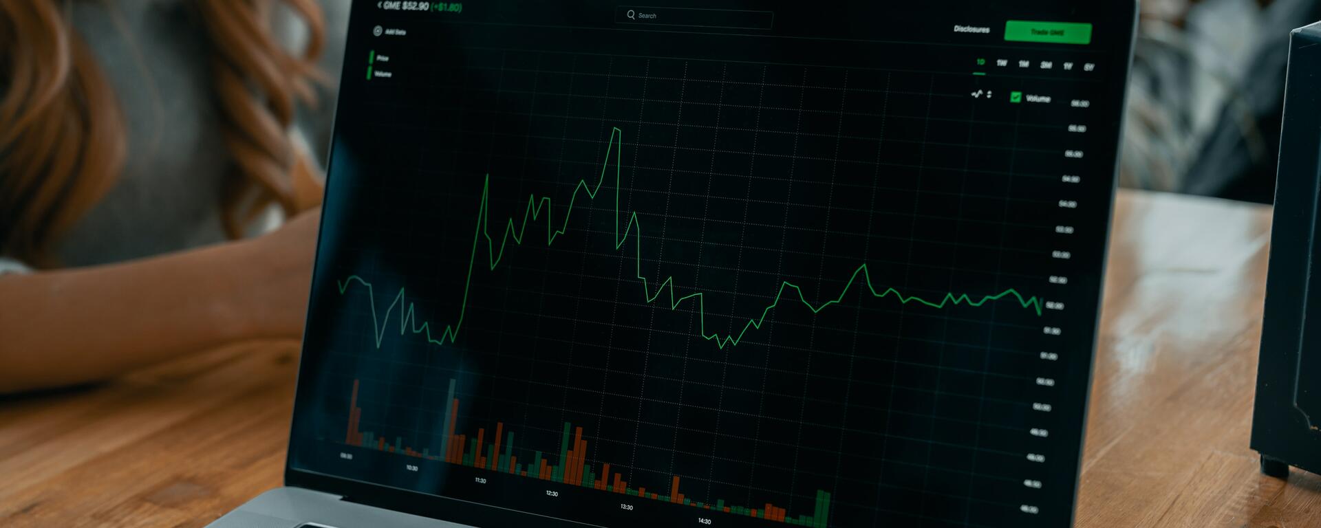 A laptop shows a financial chart on its screen