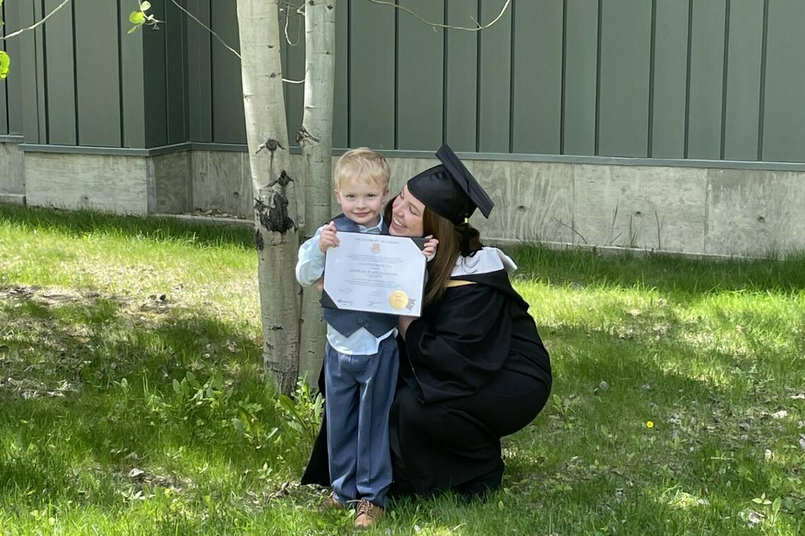 woman in graduation cap and gown with her young son