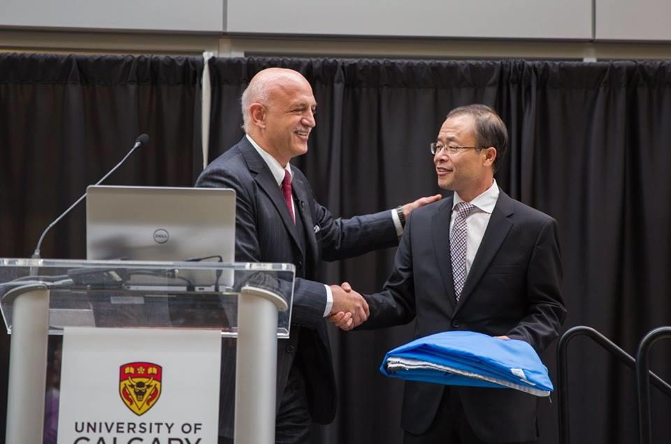 WHO delegate Bedirhan Üstün presents the WHO flag to Collaborating Centre Director Hude Quan at the Cumming School of Medicine in May 2015. Photo by Riley Brandt, University of Calgary