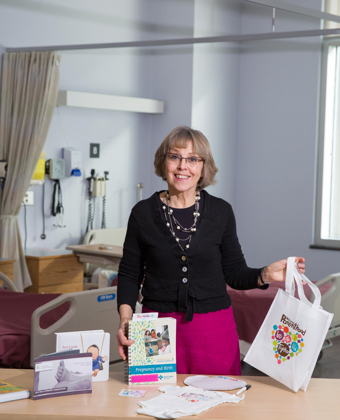 Karen Benzies, a professor in the Faculty of Nursing, along with a Welcome to Parenthood package that includes a guidebook, a onesie, and a wipe board.