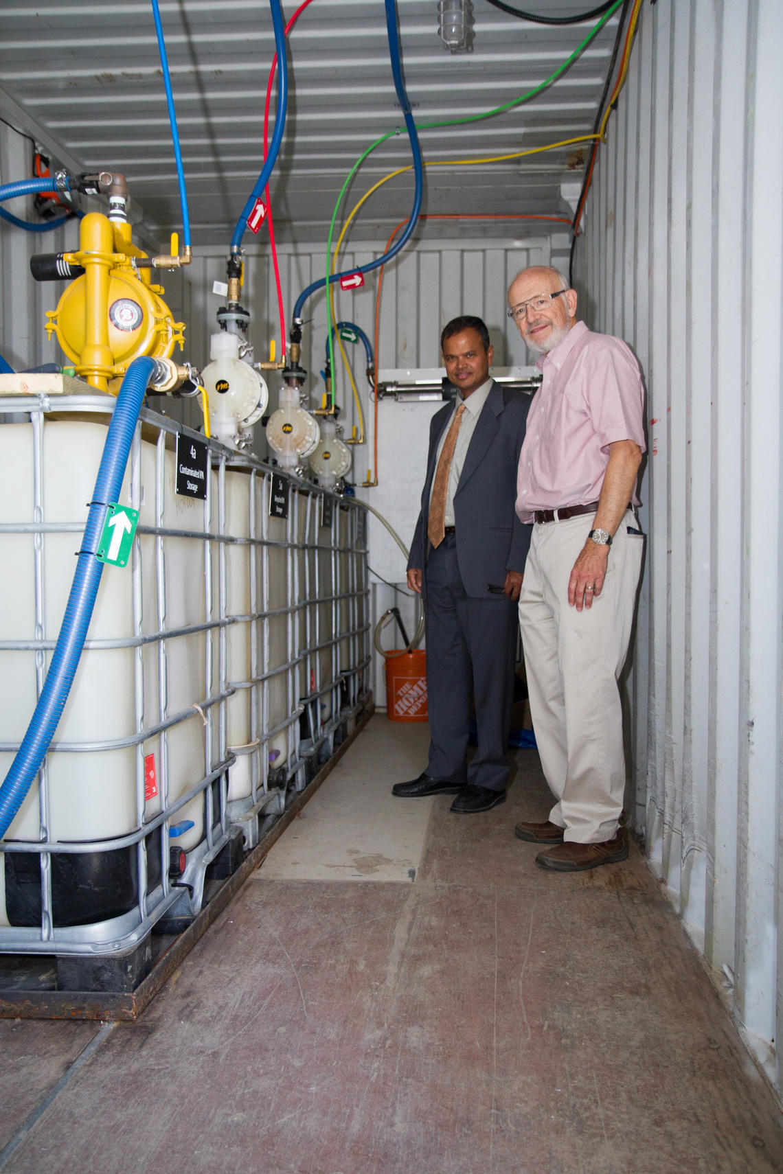 Gopal Achari, left, professor of civil engineering in the Schulich School of Engineering, and Cooper Langford, professor of chemistry in the Faculty of Science, stand inside the mobile PCB cleanup unit.