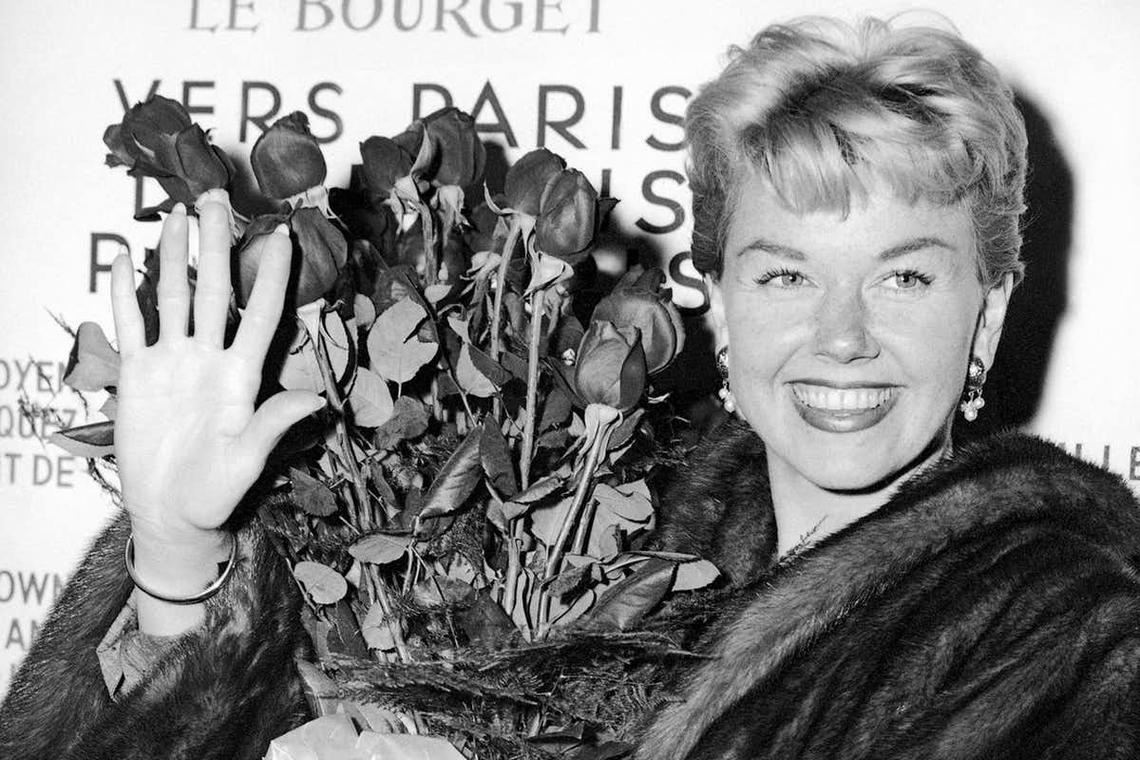 In this April 15, 1955, photo, American actress and singer Doris Day holds a bouquet of roses at Le Bourget Airport in Paris after flying in from London.