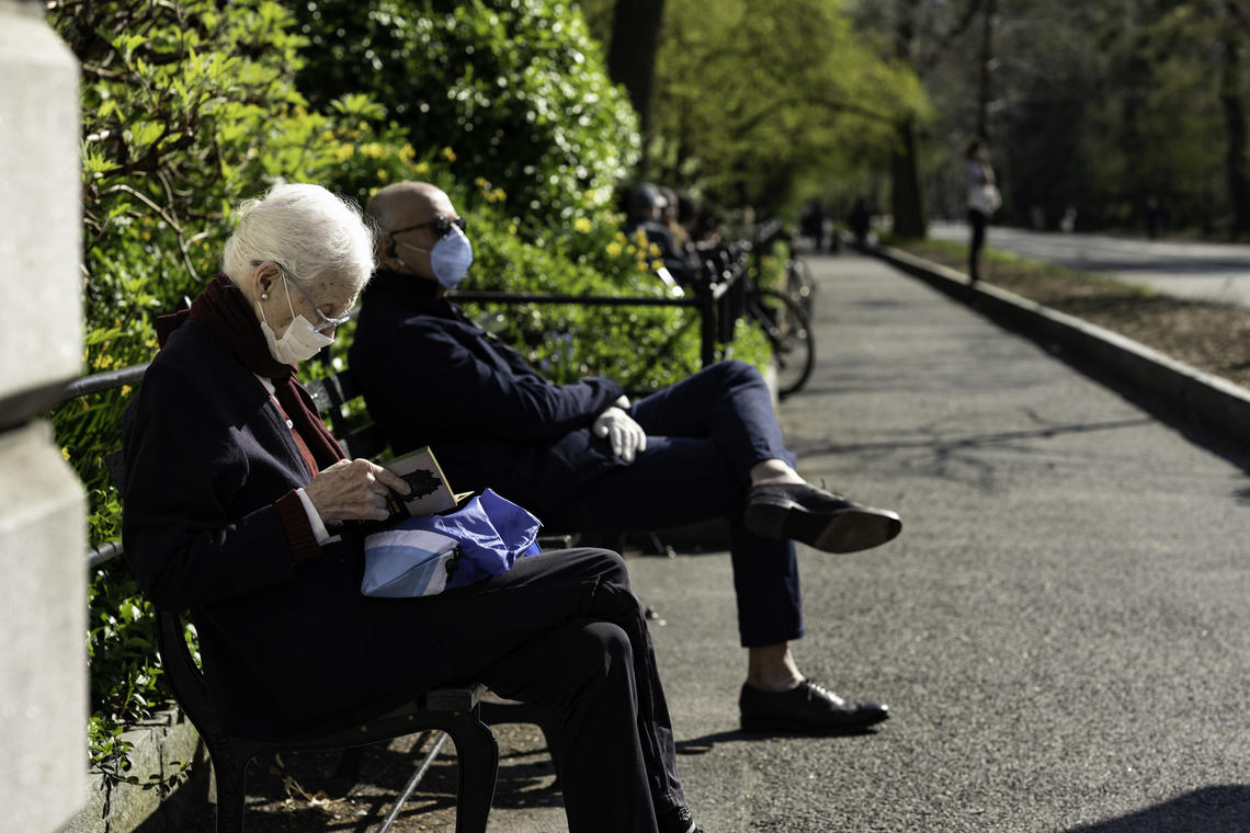 Older adult on park bench with mask on