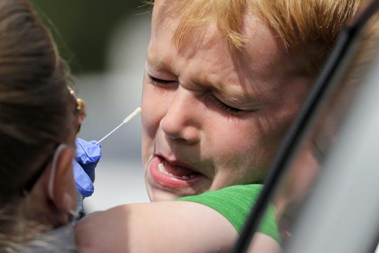 Alex Rodgers, 6, cries and tries to squirm away from a medical assistant attempting to take a swab sample up his nose at a drive-thru coronavirus testing site in Seattle on April 29, 2020. Preparation and a coping plan could have made this an easier experience.