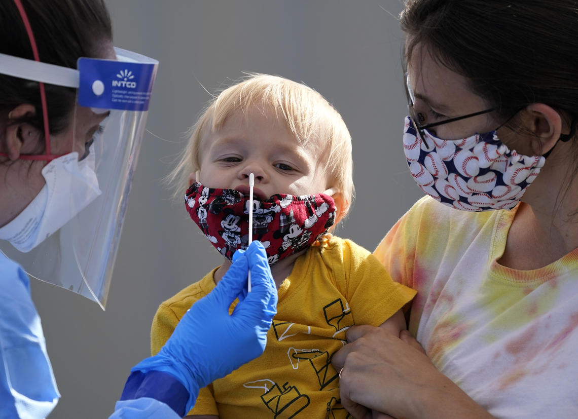 One-year-old Quentin Brown is held by his mother, Heather Brown, as he eyes a swab while being tested for COVID-19 at a new walk-up testing site at Chief Sealth High School in Seattle on Aug. 28, 2020.