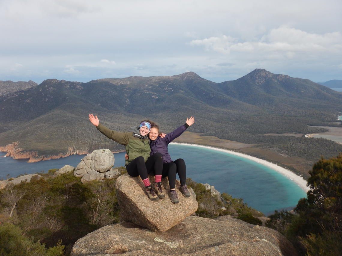 Kira Makuk (left) and her friend Grace Kennedy sit on a perch overlooking Wineglass Bay in Tasmania, Australia