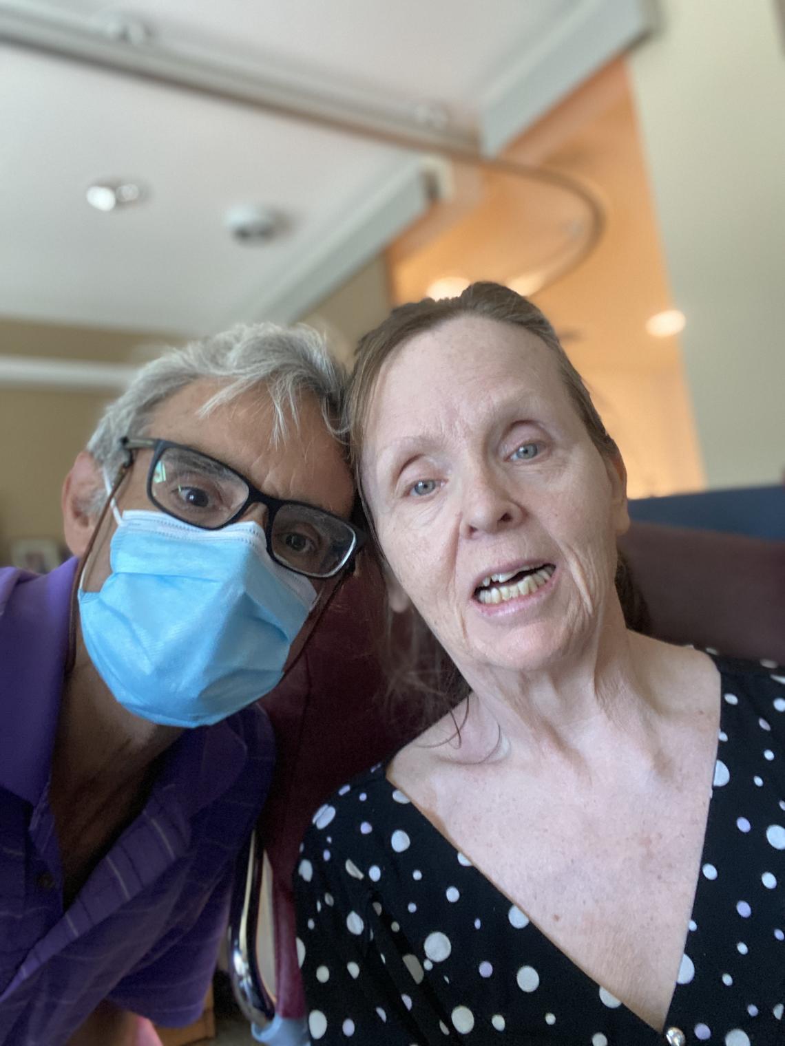 Daniel, wearing a face mask, poses next to his wife Janet who lives in a long term care facility