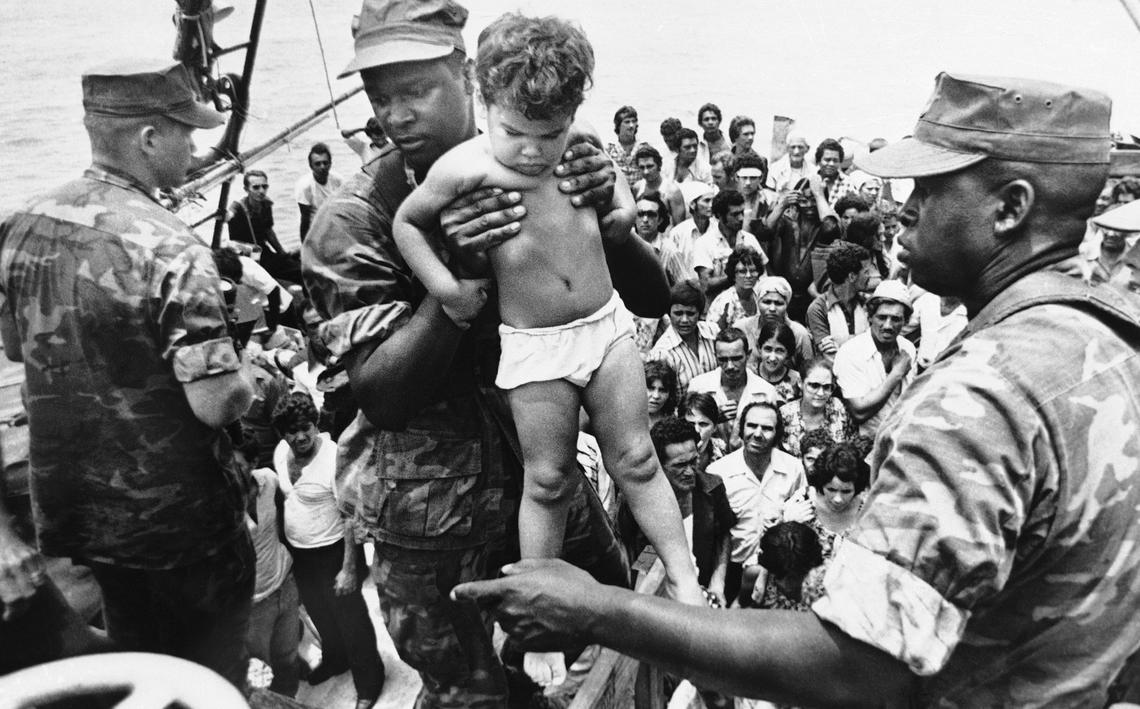 a U.S. Marine helps a young Cuban child off a refugee boat in Key West, Fla.