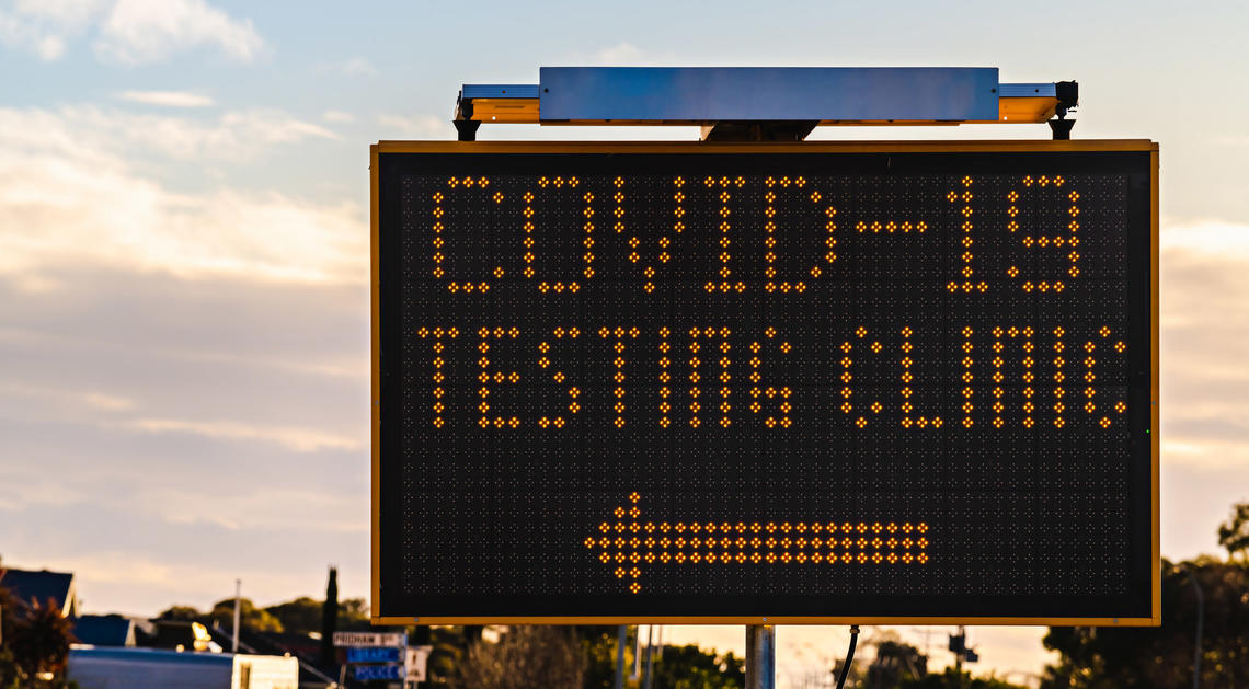 A road sign reads "Covid-19 testing clinic" with an arrow pointing to the left
