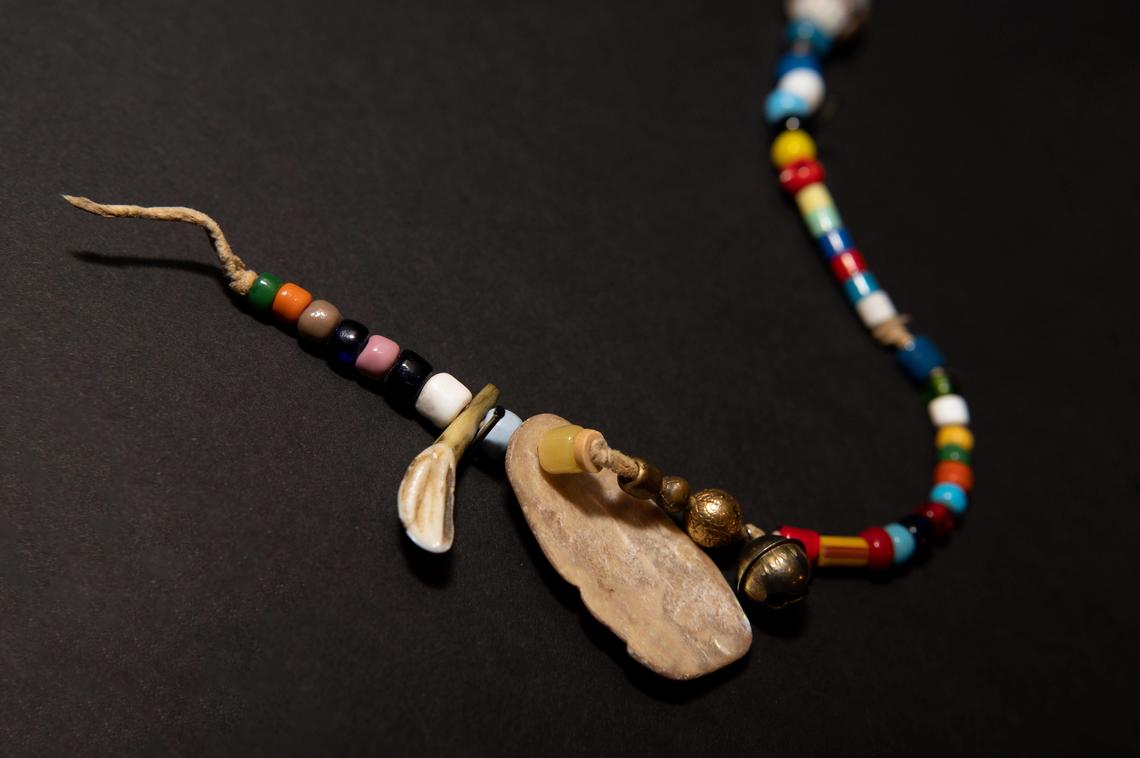 Indigenous trade bead necklace with an elk tooth and a shell. From the Nickle Numismatic Collection.