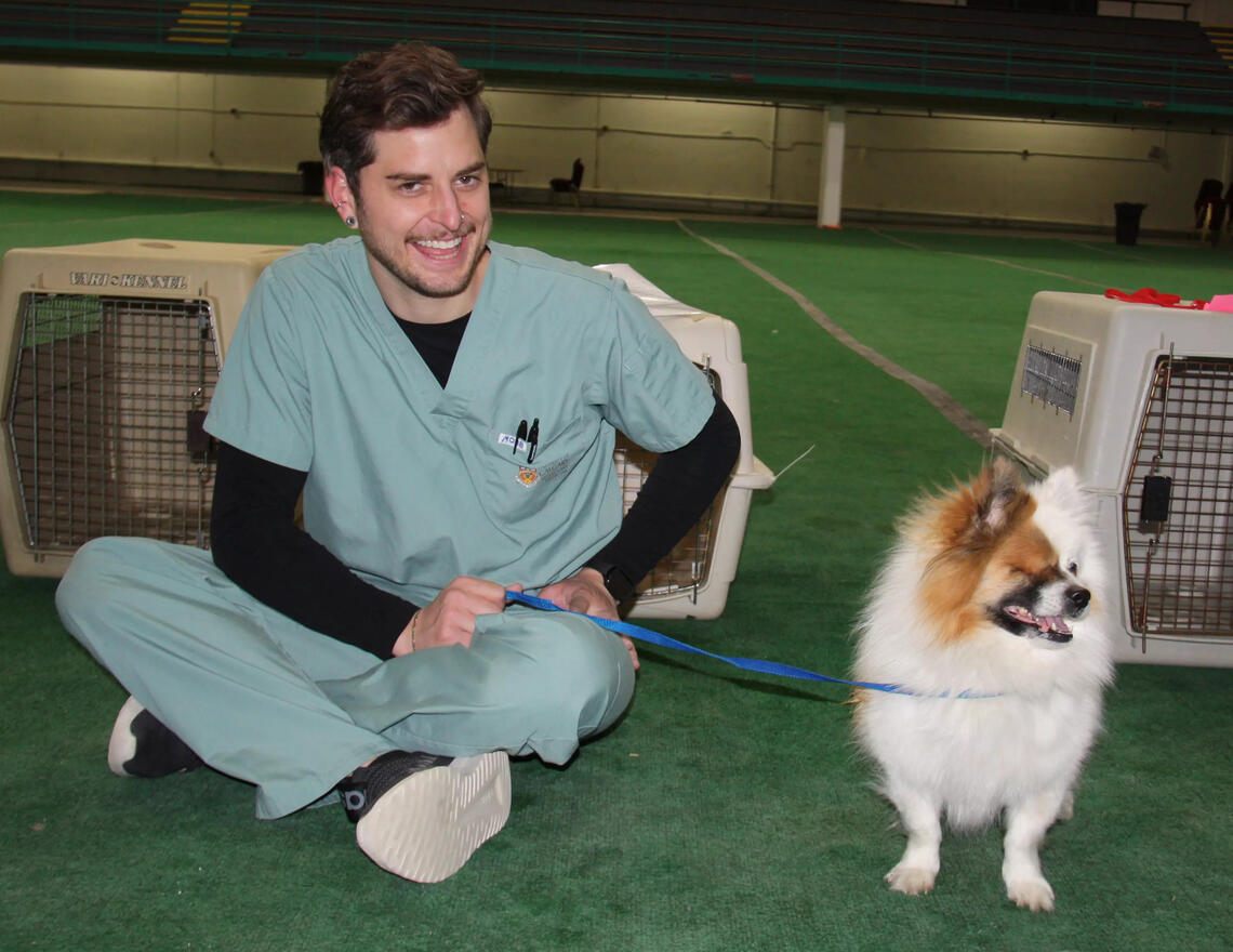 UCVM tech assistant, Tomas Preston, hangs out with Gilbert the dog before the animal's preventative veterinary care