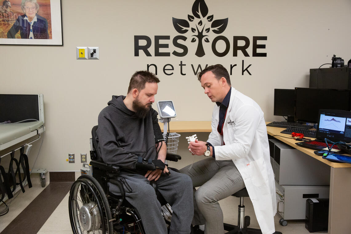Dr. Aaron Phillips shows Nick Wiltshire the spine stimulation implant that will regulate his blood pressure.
