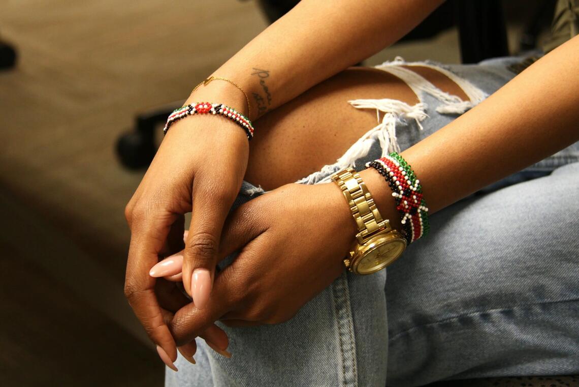 Two hands wearing multiple bracelets