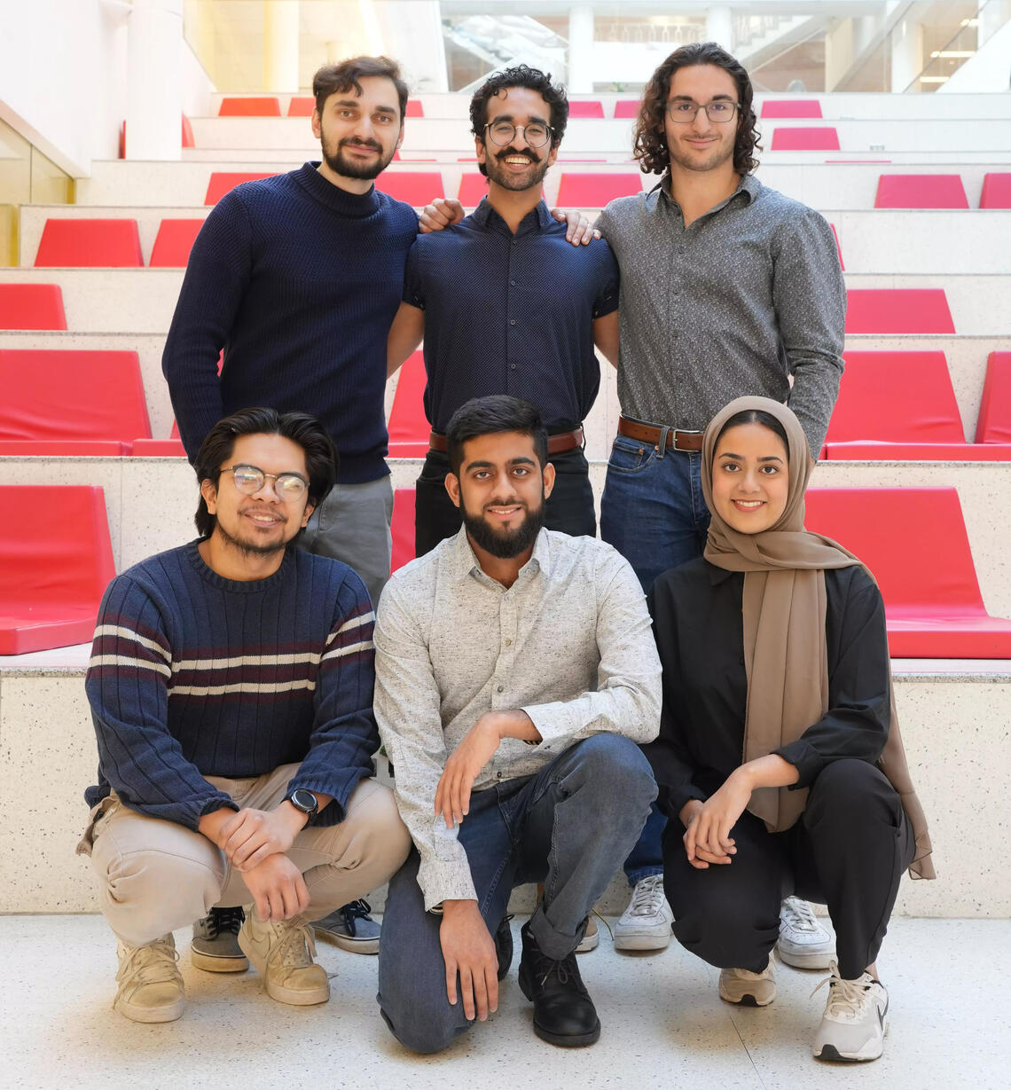 A group of people stand in front of red steps