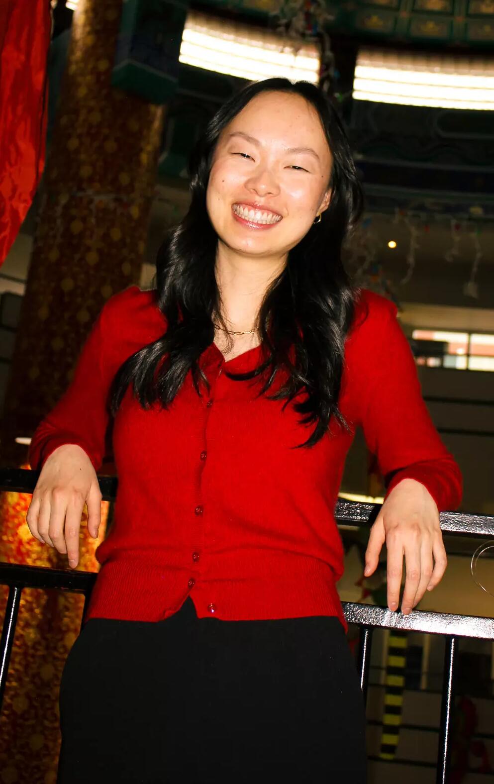 A woman in a red shirt smiles at the camera