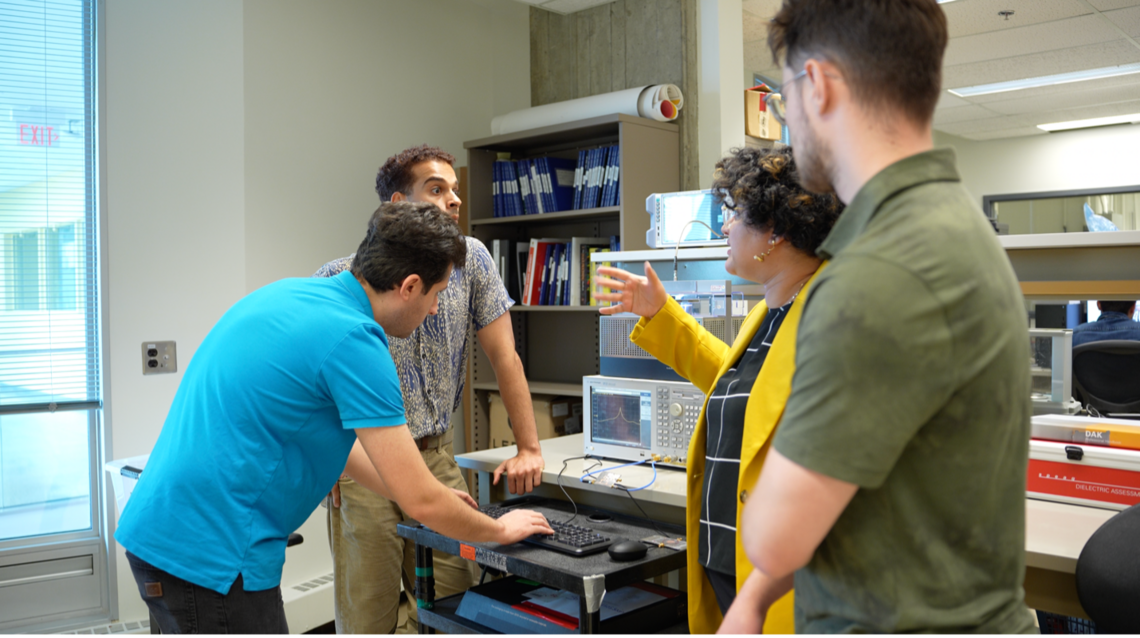 Dr. Zahra Abbasi and 3 of her students (all male),  in the Calgary Sensors Lab standing around a computer