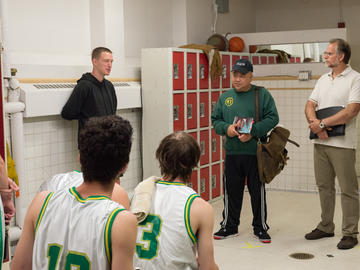 People gathered in a locker room with a film crew