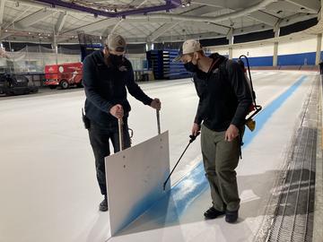 Oval team members paint lines on the ice