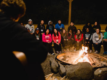 Students sit around the Camp LEAD campfire