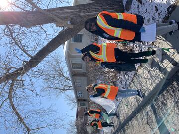 Volunteers wearing high-vis vests walking in community, picking up litter and waste.