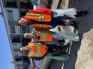 Volunteers wearing high-vis vests and holding trash bags, walking in community, picking up litter and waste.