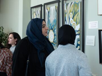 Two women in hijabs look at artwork