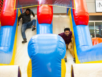 Two people race down a bouncy castle slide