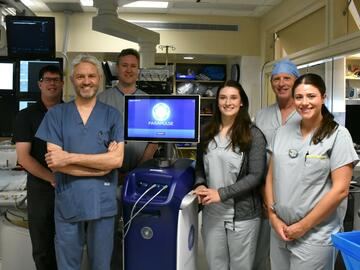 A group of surgeons stand in front of a machine