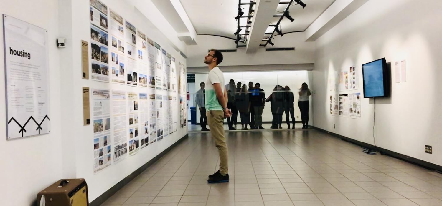 A Master of Architecture student learns about the housing situation in Tijuana while Prof. Hamels' Research Studio 6 peeks into the gallery.